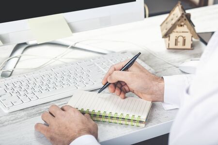 young male hands in white clothers writes something in white notebook, no face, writing notes, poetry, stories, doctor writes recommendationsの写真素材