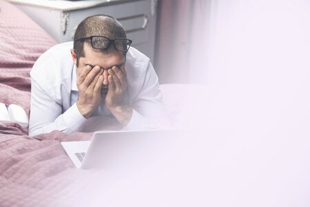 Young tired businessman rubs his eyes after work