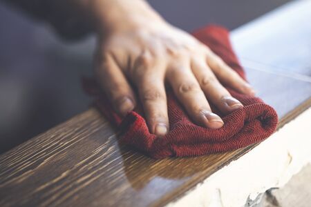 young woman cleans a table with a red rag