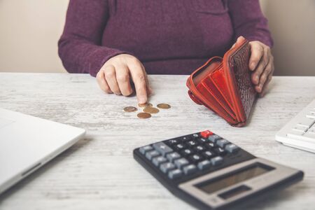 woman hand house model with coins and calculator on table