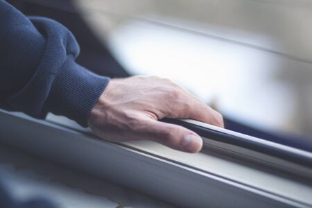 The man's hand opens the window. Ventilating a house in hot weather.の写真素材