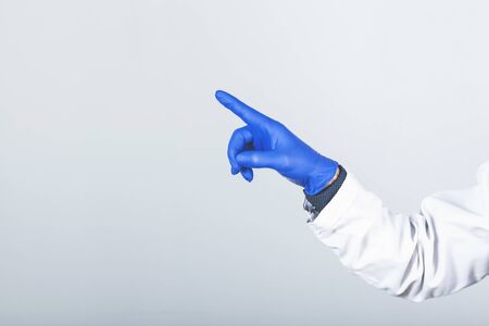Male doctor in surgical gloves pointing something over grey background.の写真素材