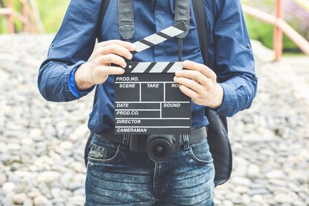 Young man holding clapper board in the park