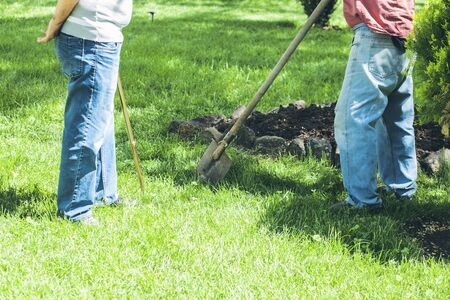 two workers are working with shovels in the park