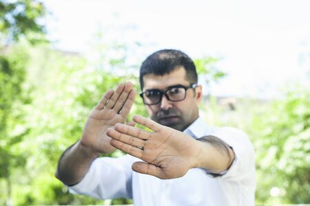 Young man  with his hands shows stop in the nature