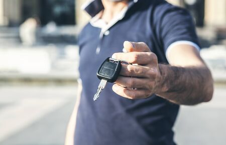 man hand car key on city background 