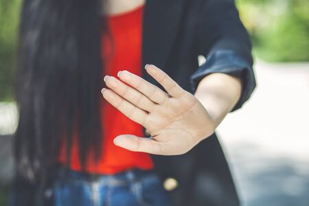 woman hand stop sign on park backgroundの写真素材