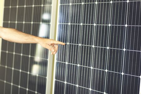 Young man shows by hand in side of solar panelsの写真素材
