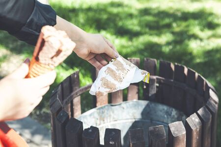 Close up of a woman hand throwing trash into a bin in the parkの写真素材