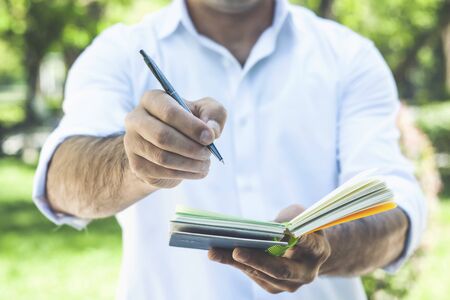 young businessman writes in a notebook while standing on the streetの写真素材