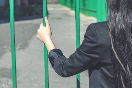Womans hands holding on to a metal fenceの写真素材