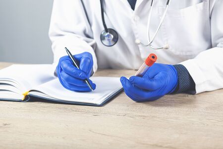 Male doctor writes notes on the clipboard in the hospitalの写真素材