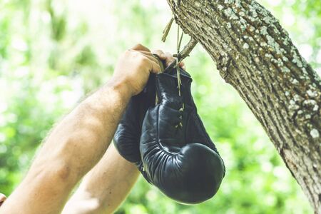man hands holding a pair of boxing gloves on the background treeの写真素材