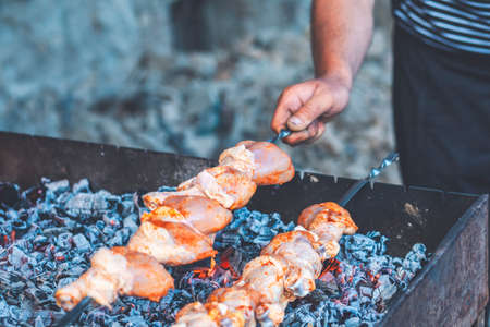 A man fries meat while cooking barbecue. Cooking meat in nature. Close-upの写真素材