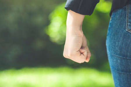 angry woman fists on the green park backgroundの写真素材