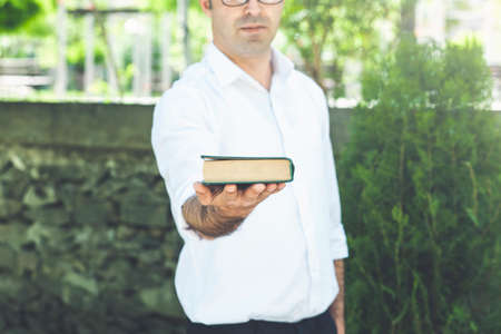 Close-up of hand holding one book on green background