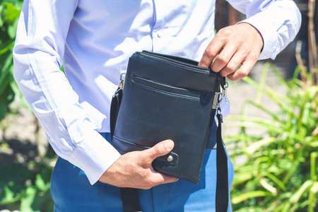 Young businessman holding and opening a leather briefcaseの写真素材