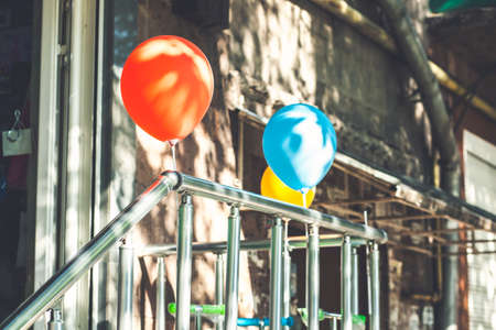 Red and white balloons are attached to the porch railing. Store opening. Bright sunlight and shadows. Festive street backgroundの写真素材