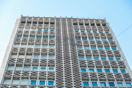 Facade of high rise building with sunlight and blue sky background.