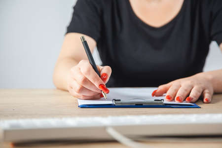 A woman writes with a pen in a notebook.の写真素材