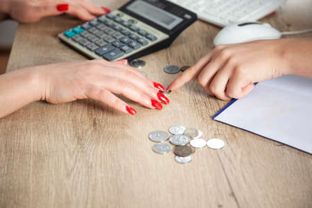 Young girl sorting, grouping her coins on table with laptop beside.Young girl counting her money on her table with laptop.Young girl saving a money.Girl's creativity, imaginationの写真素材