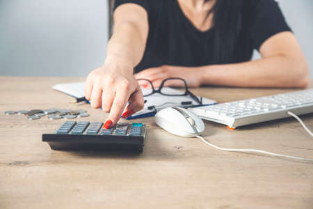 Female hands with red nails on a calculator keyboard.の写真素材