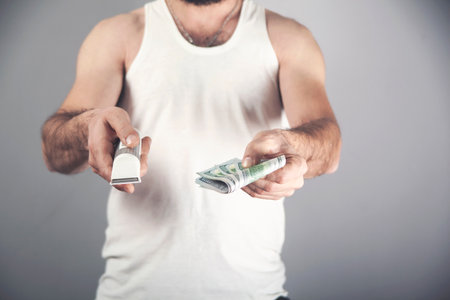 Hand holding hair clipper and money on gray background