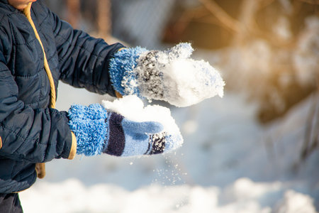 Little boy walking and having fun playing with fresh snow during snowfallの写真素材
