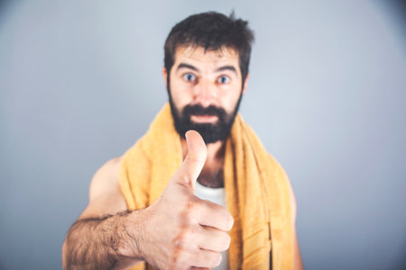 Man with wet hair in the bathroom. Thumb up.の写真素材
