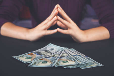 Woman holding and counting cash money american dollars in her hands on black table background.の写真素材