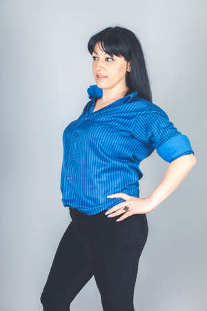 Elegant young woman dressed in black skinny jeans, blue shirt posingの写真素材