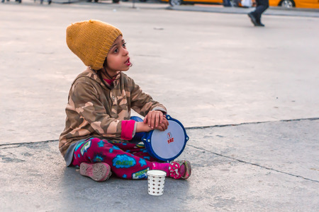 ISTANBUL, TURKEY - APRIL 18: Winning money by playing tambourines little girl in the street on April 18, 2015 in Istanbulのeditorial素材