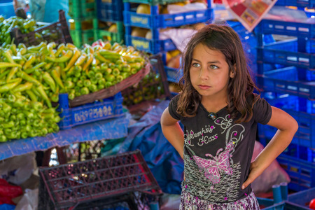 IZMIR, TURKEY - JUNE 24: The little girl selling vegetables in public market on June 24, 2015 in Izmirのeditorial素材