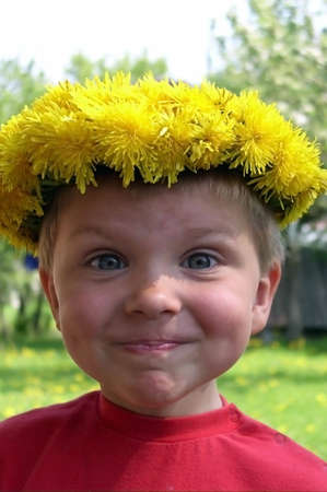 A smiling child with a wreath of dandelionsの写真素材