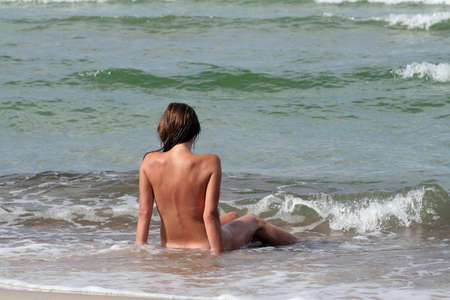A woman sitting in the waving seaの写真素材
