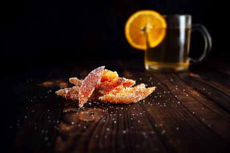 Orange peels in sugar. Candied fruit from aplsin. Orange marmalade on a wooden brown table with a black background. Tea with sliced orange. Empty space for text.の写真素材
