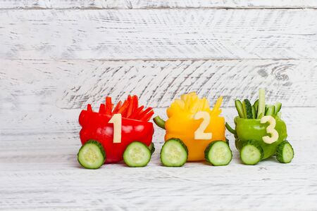 Multi-colored peppers. Red, yellow, green peppers as a traffic light. DIY educational toy for children on a white background. Children's train made of food with numbers.の写真素材