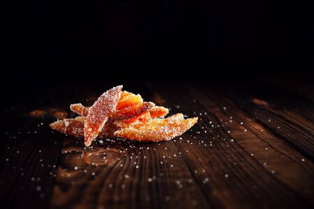 Orange peels in sugar. Candied fruit from aplsin. Orange marmalade on a wooden brown table with a black background. Empty space for text.の写真素材