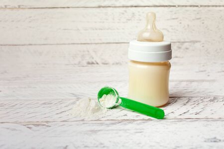 Baby bottle with milk formula on a white wooden background with empty place for text. Milk powder for the baby. Artificial nutrition of a newborn.の写真素材