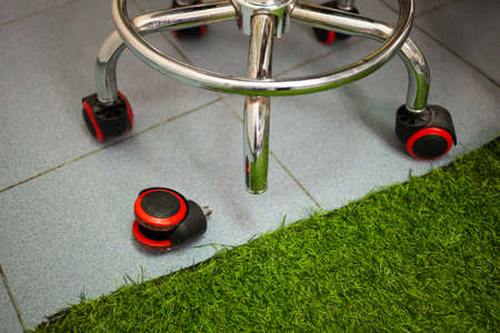 The office chair is broken, the wheel from the chair fell off and lies on the floor. Broken office chair. The wheel is separate from the chair.の写真素材