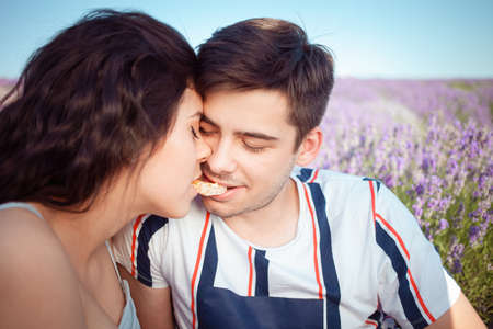 A couple in love under a white umbrella on a lavender field love each other, hug, look happy. Empty space for text. Blue sky, purple lavender.の写真素材