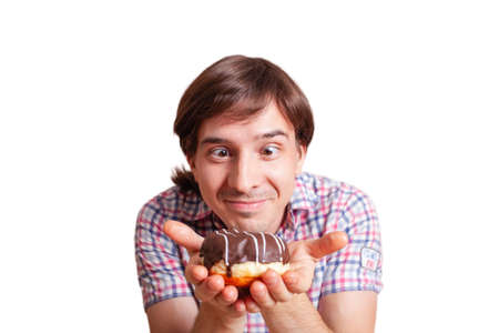 A man chooses between white and black chocolate. Funny man looks at the chocolate donut, a very funny photo on a white background. Empty space for text. A man loves sweets chocolate.の写真素材
