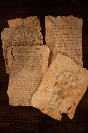 Magical writings, piles, aged paper, candles, wooden brown background Halloween celebrationの写真素材