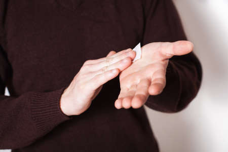 Close up on midsection of young caucasian man hands wiping using white alcohol tissue, eaning napkin...