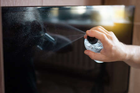 The man cleans the TV from the dust with a alcohol solution. Disinfection from coronavirus. The girl...