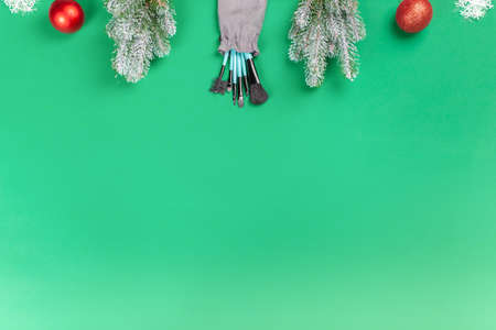 Christmas, New Year's background for make-up artist. Make-up brushes, Christmas decorations, spruce. Empty space for text.の写真素材