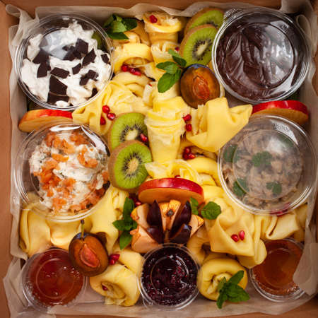 Delivery of food in a box, delicious and fresh food. Convenient boxing for eating at home, at work, in nature. Beautiful pancakes with fruit, chocolate, salmon, liverの写真素材