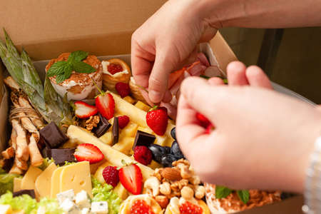 A man decorates a box of fruit and chocolate strawberries. Natural light from the windowの写真素材