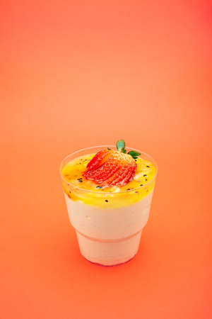 Sweet dessert in glass with biscuit, Strawberries fruit and whipped cream. Empty space for text. on an orange backgroundの写真素材