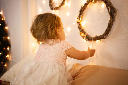 A little girl in a Christmas photo studio. Boke, yellow lights, happy baby.の写真素材